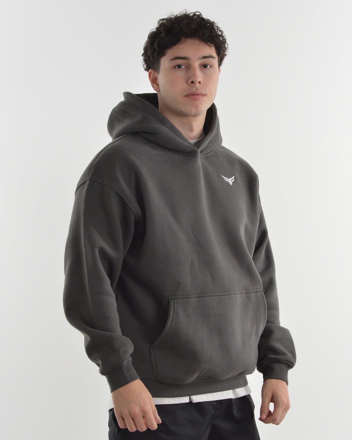Person wearing a dark gray hoodie and black shorts on a white background