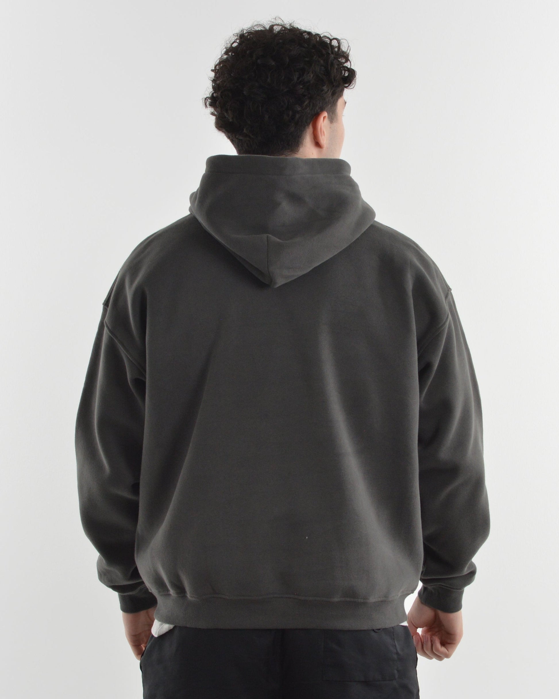 Person wearing a dark gray hoodie and black shorts on a white background