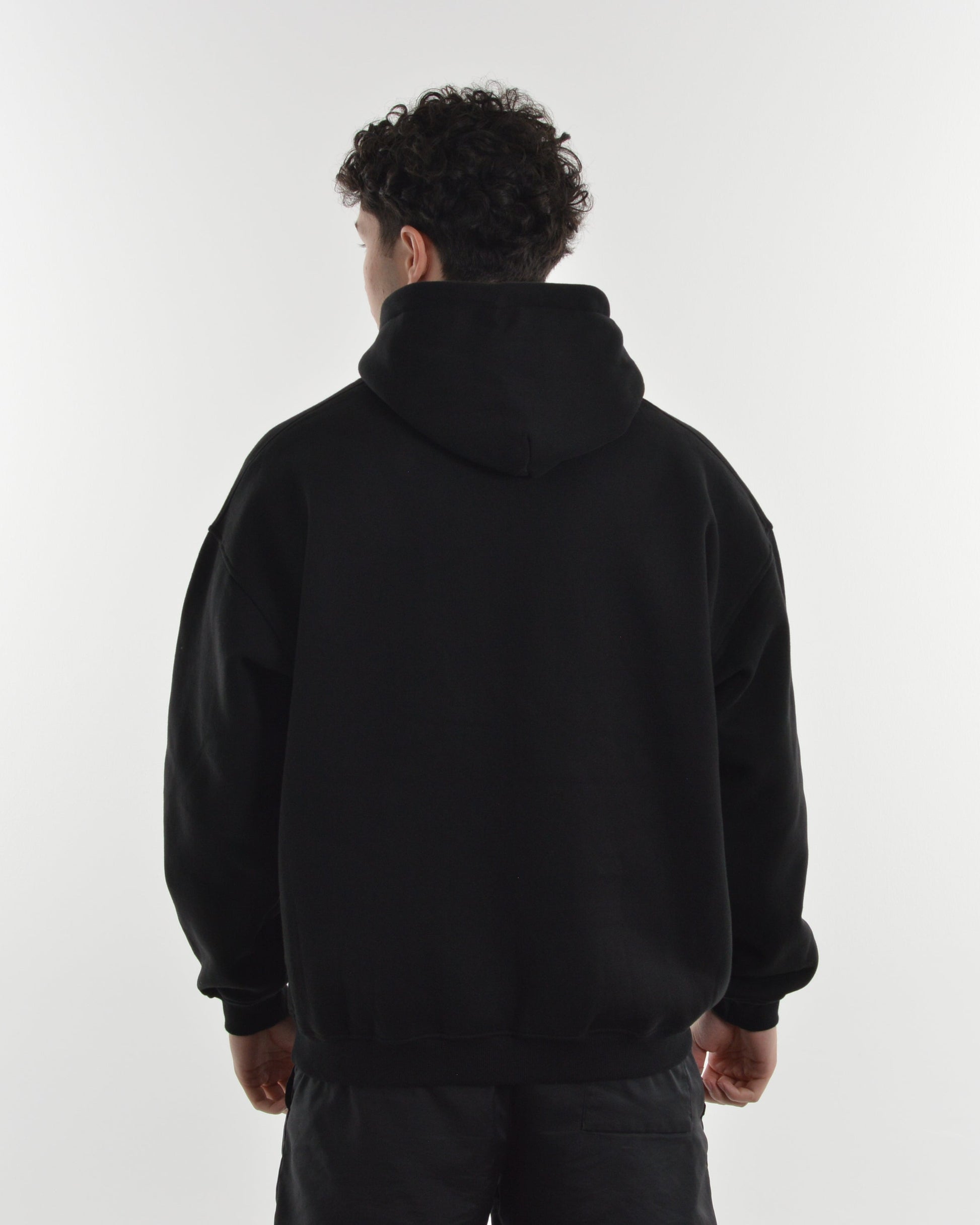 Person wearing a black hoodie from behind on a white background